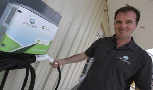 Kent Rathwell with a Sun Country Highway charging station at Peavey Mart in Red Deer, Alberta.