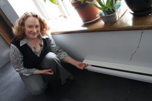 Serena Kaba shows the electric baseboard heaters that are the second backup after a fireplace to their passive solar heated home.
