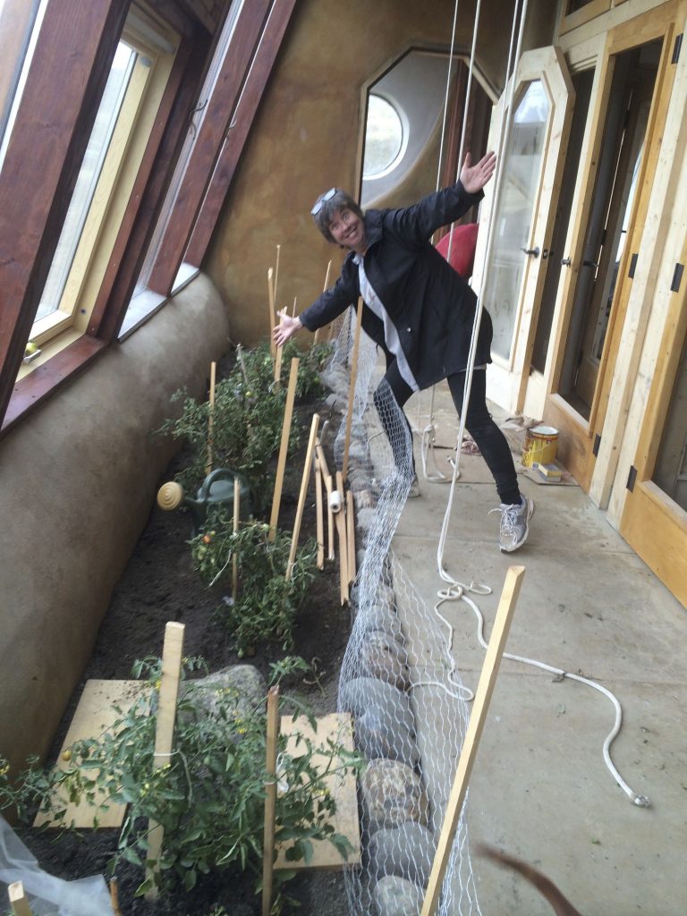 Dawn Kinney in the greenhouse, which also serves as the main hallway in the Earthship.